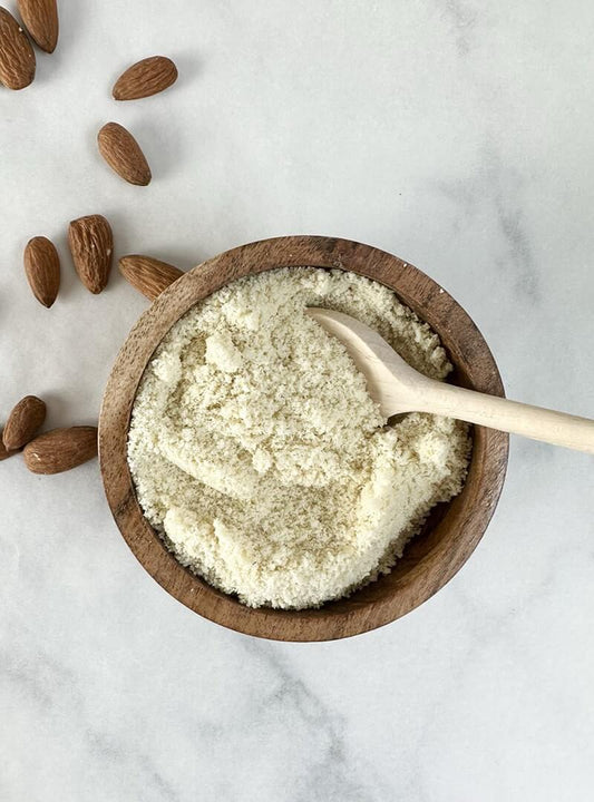 Ground almond flour in a wooden bowl with a spoon, prepared from almond pulp