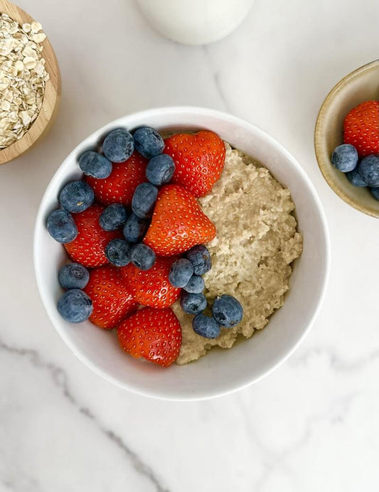 Bowl of oatmeal topped with fresh strawberries and blueberries