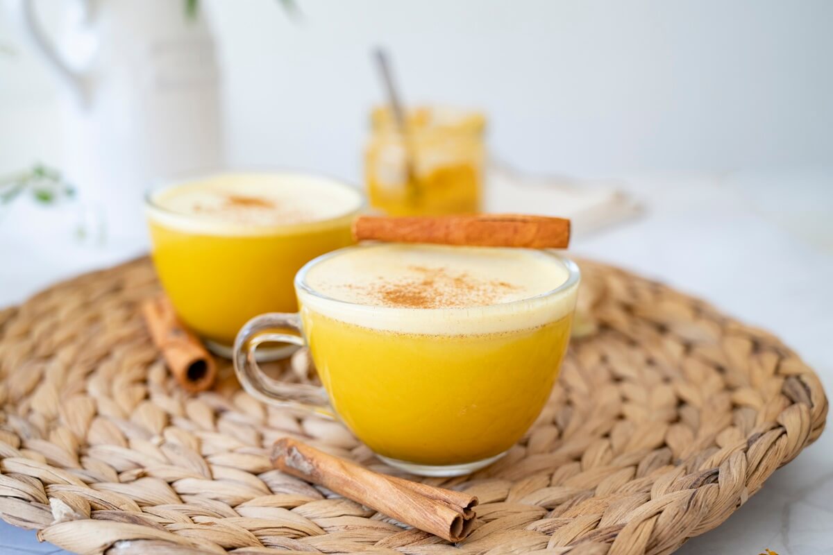 Two glasses of golden milk topped with cinnamon, made from coconut, turmeric, and ginger. 