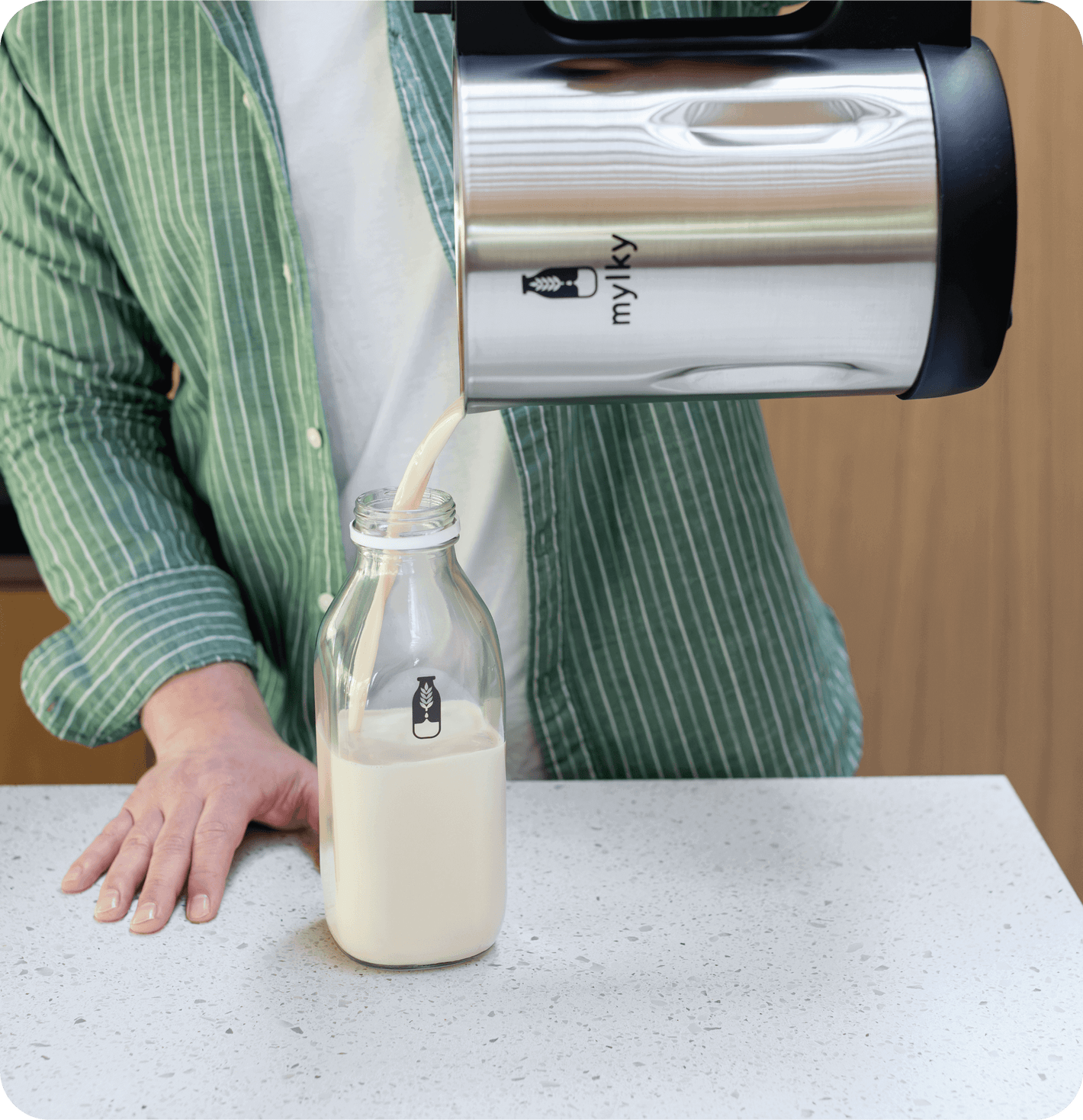 Pouring plant-based milk from Mylky machine into a glass bottle